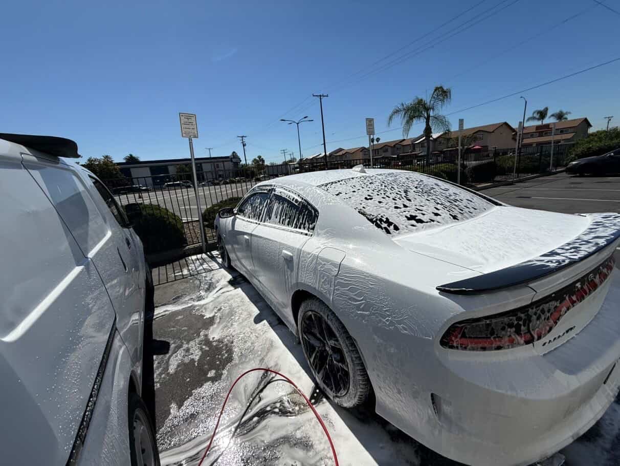 White Dodge Charger covered in thick foam during exterior wash